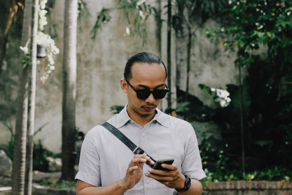 Um homem andando na rua e acessando do seu celular os dashboards graças ao Programmers REACT