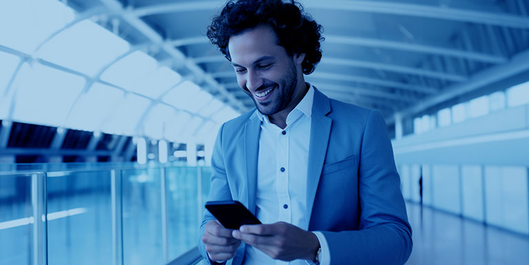 um homem segurando e olhando um celular mostrando a jornada Inovação de Aplicações de uma empresa